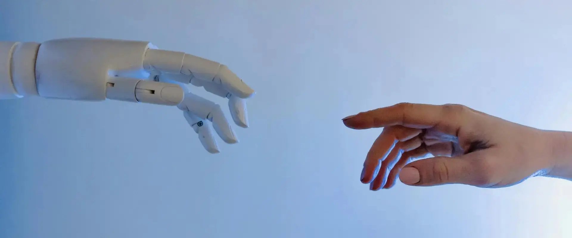 Mano de robot y de persona acercándose como en la pintura de la creación de Adán de Miguel Angel